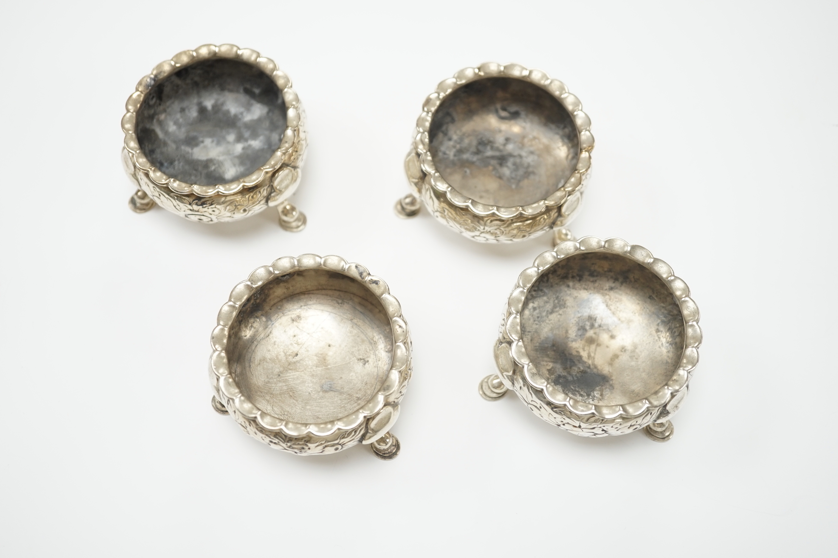 A set of four George II silver bun salts, William Gilchrist, Edinburgh, 1755?, diameter 64mm, 11.1oz, with later? embossed decoration.